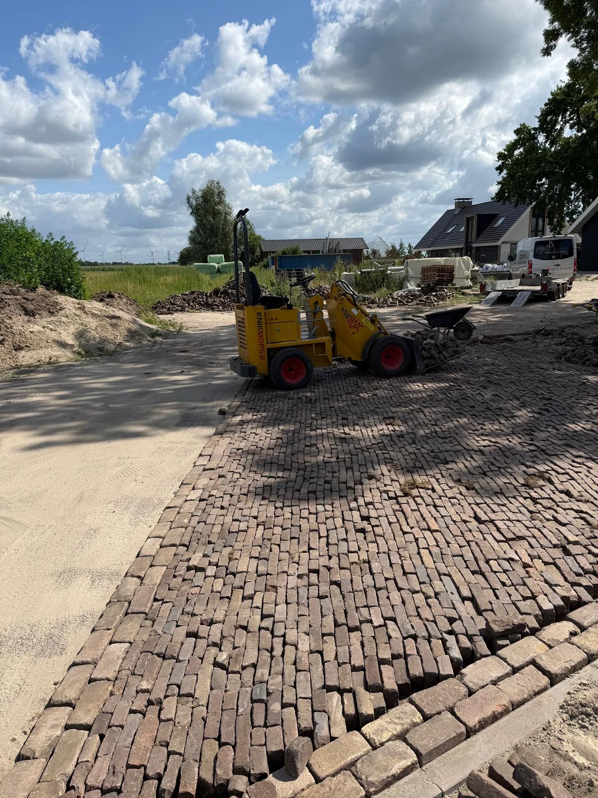 Shovel bij het klinkerwerk op het erf