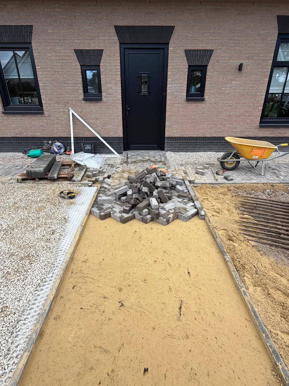 Voorbereid zandbed en kantstroken bij de voordeur