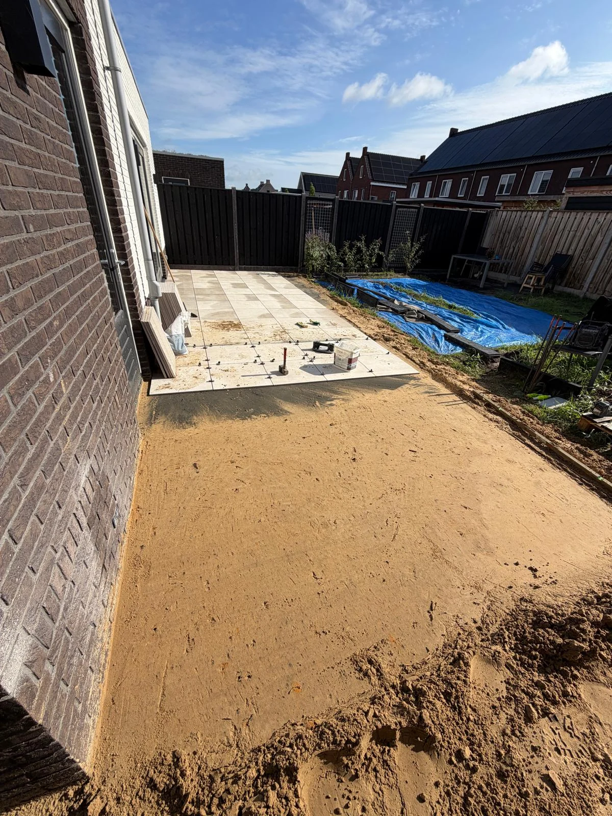 Zandbed en eerste tegels langs de woning
